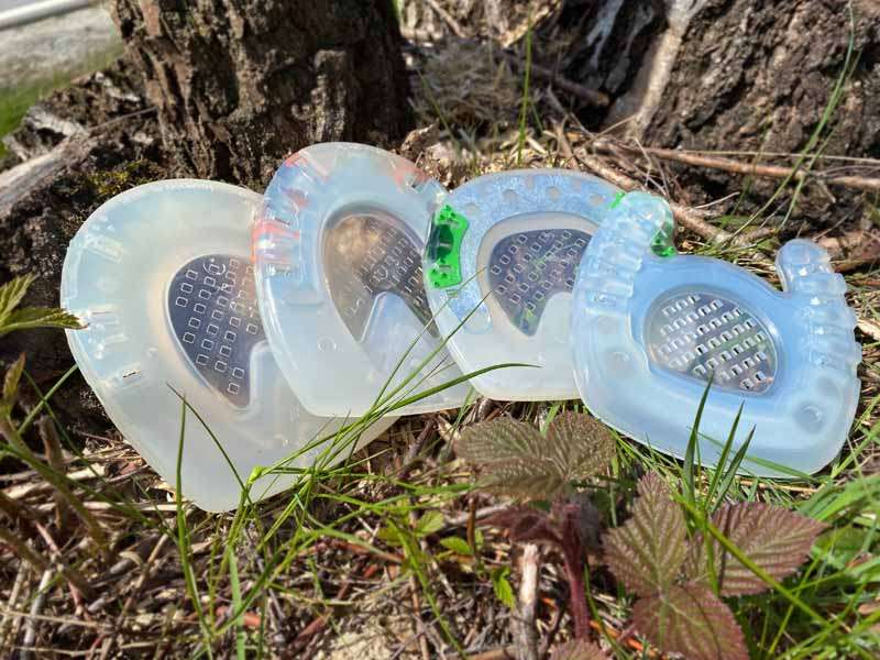 Varios herrajes de plástico con suela cerrada están tirados frente a un tronco de árbol.