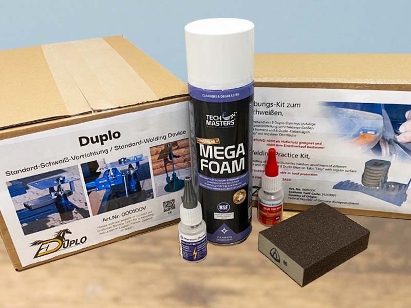 hoof cleaner, abrasive block, instant glue, a plastic welding device and welding practic kit placed on a wooden floor