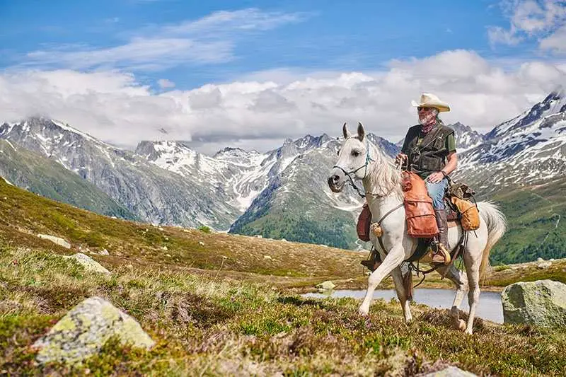 Weißes Pferd mit Reiter in den Bergen.