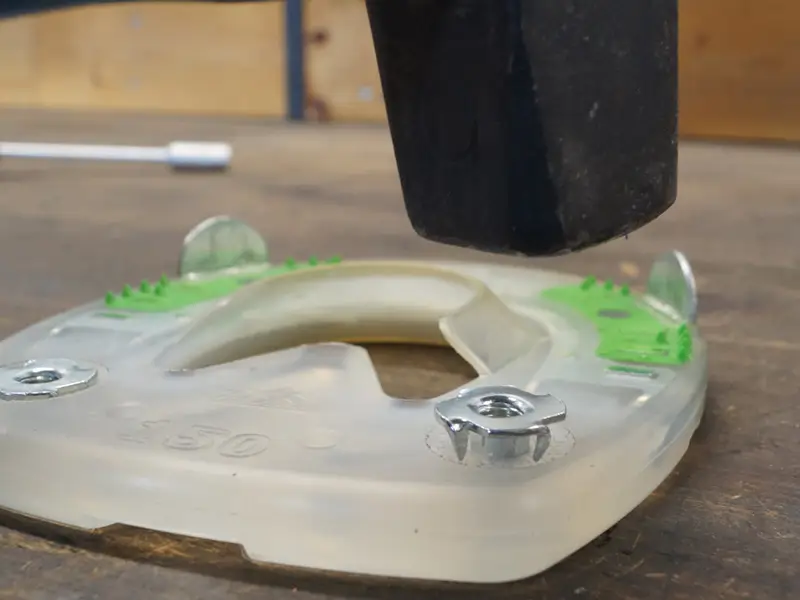 A farrier drives a stud nut into the plastic web of an alternative horseshoe.