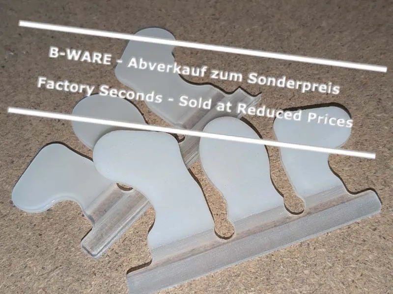 zwei aussortierte Wolf Busch Basic Klebelaschen in Größe 4 liegt auf einer Werkbank. Sie haben unterschiedliche Fehler, sind aber funktionell in Ordnung und werden daher zum Sonderpreis verkauft.