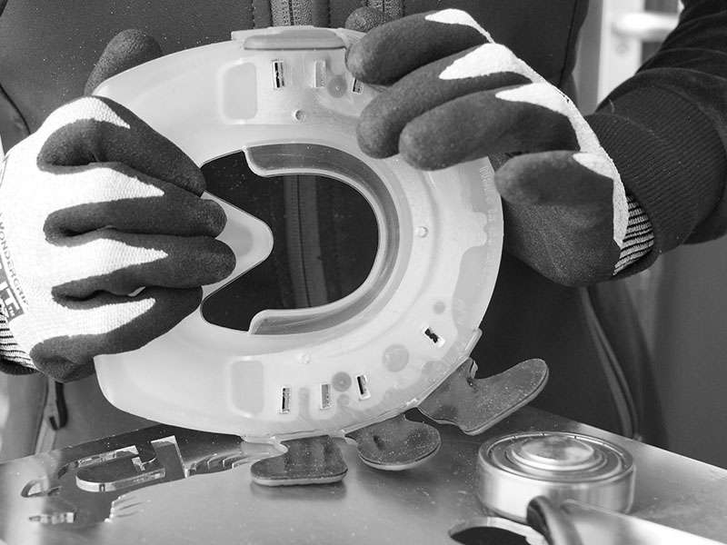 A farrier prepares a glue-on shoe for a horse's hoof consisting of a synthetic shoe and Wolf Busch glue-on tabs