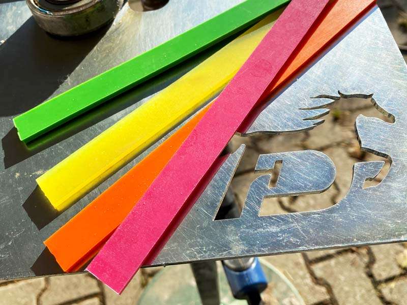 Tiras de color verde, amarillo, rosa y verde para herraduras con revestimiento de plástico sobre una placa metálica