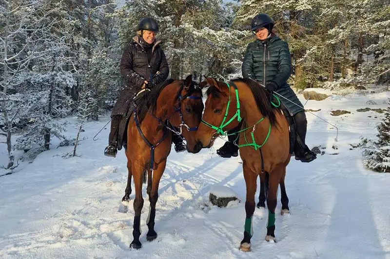Die Reiterinnen von Stockholm Endurance reiten mit ihren Pferden im Winter durch den Schnee.