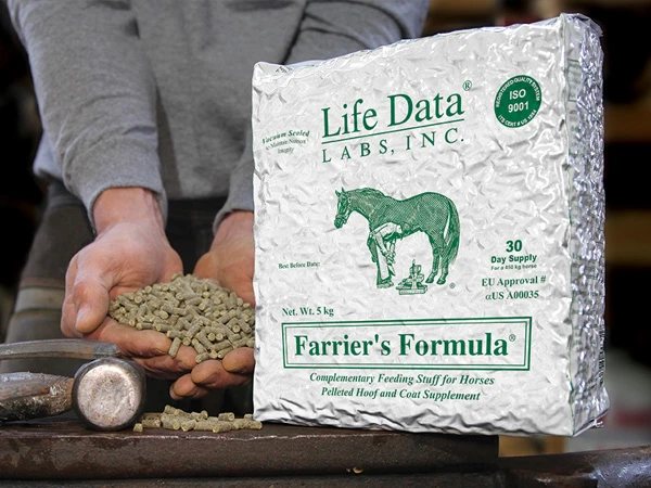 Verpackung des Ergänzungsfuttermittels Farrier's Formula von Life Data Labs für Pferde, mit einem Hufschmied, der Pellets in der Hand hält. Das Futter steht auf einem Amboss mit Hufpflegewerkzeugen im Hintergrund.