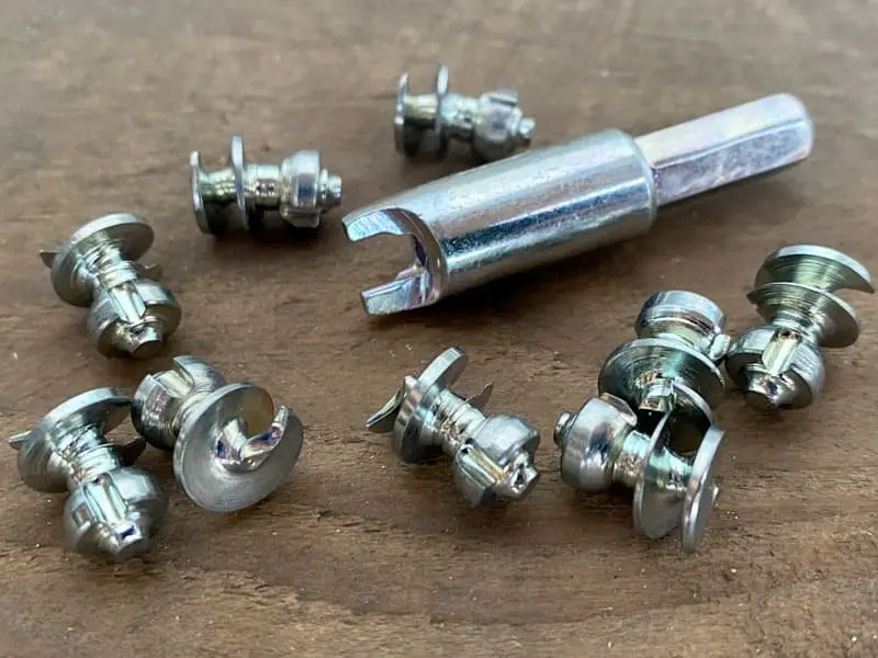 viele Spikes und der passende Adapter liegen auf Holzbrettern; Spikes sind ähnlich wie die Stifte beim Hufeisen eine Vorstufe zu Stollen