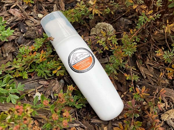 Eine Pinselflasche von Hoofsmooth liegt auf einem von Zweigen bedenckten Untergrund