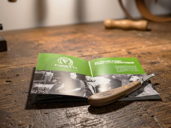 Double S Fusetti: Hufmesser Big Horn liegt auf einer Werkbank. Darunter liegt ein Produktkatalog von Doulbe S Fusetti