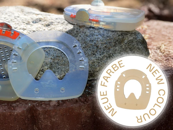 Imagen para ilustrar el nuevo color beige de las cuñas para herraduras compuestas con revestimiento de plástico amortiguador. Al fondo, sobre una piedra, se ven herraduras y cuñas.