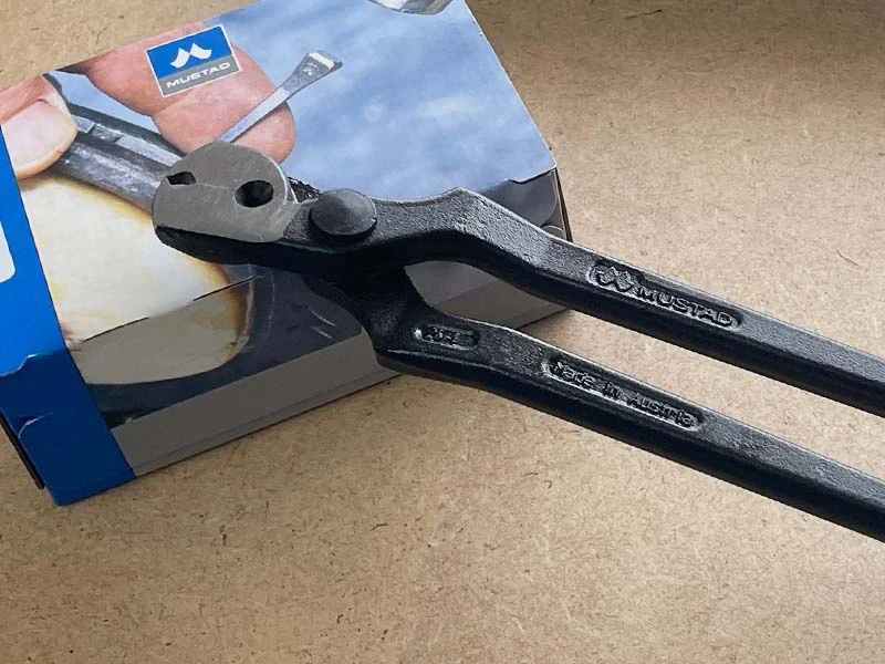 A nail puller from Mustad lying on a box of Mustad horseshoe nails.