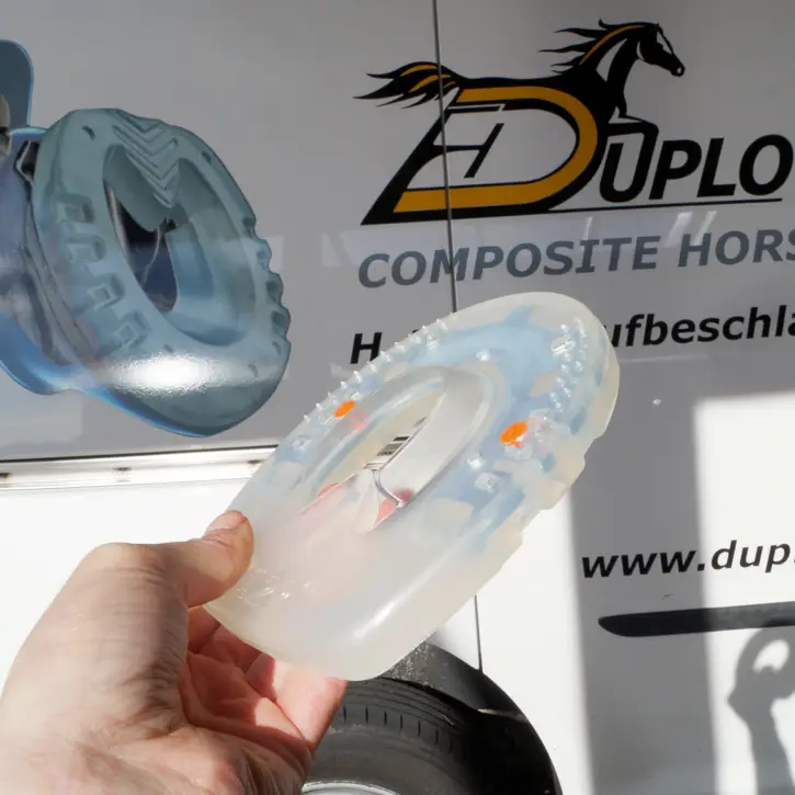 Detailansicht eines runden Duplo Nailless in der weicheren Standard Variante, in der Hand des Hufbearbeiters. Im Hintergrund steht der Beschlagsbus