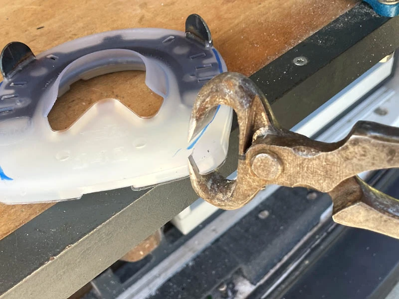 Una herradura sintética ajustada con una tenaza de corte.