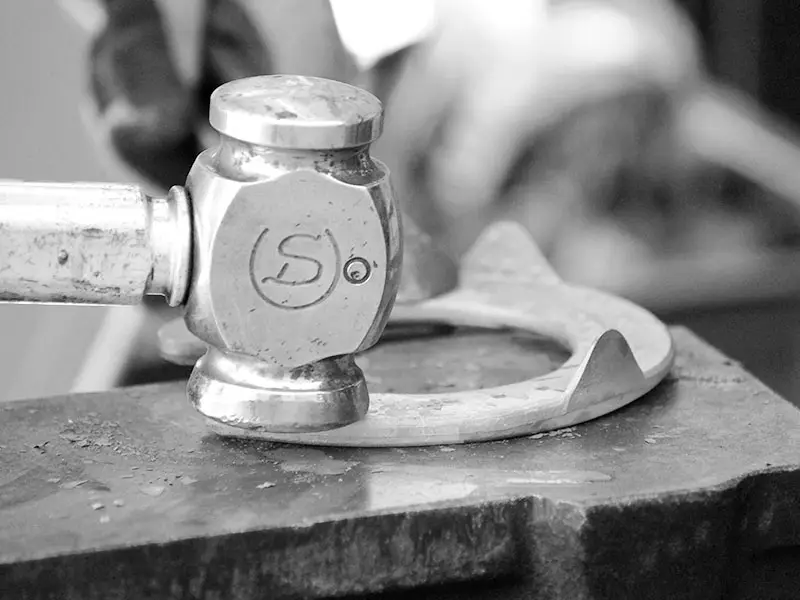 Close-up of the Double S forging hammer head while shaping a horseshoe on the anvil.