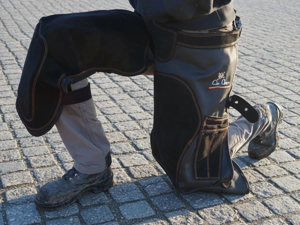 Una herradora lleva el modelo Ale de Con Cuero. Está arrodillada y protegida por un grueso acolchado en la zona de la rodilla.