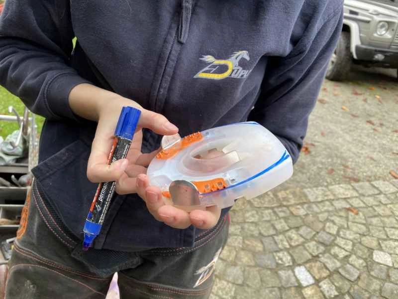 Die Hufschmiedin hält einen alternativen Beschlag in der Hand. Die Hufform des Pferdes ist bereits angezeichnet aber der Beschlag wurde noch nicht angepasst.