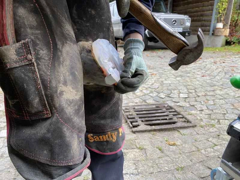der Hufschmied beim Aufnageln eines alternativen Hufschutzes mit Aufzügen