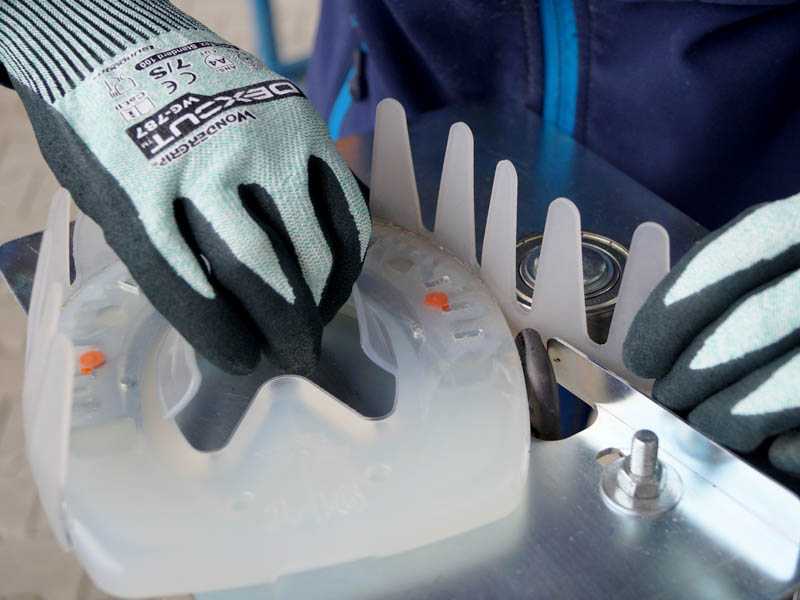 Des mains portant des gants de sécurité tiennent une plaque de base et un collier adhésif lors du soudage à l'aide d'un appareil spécial.